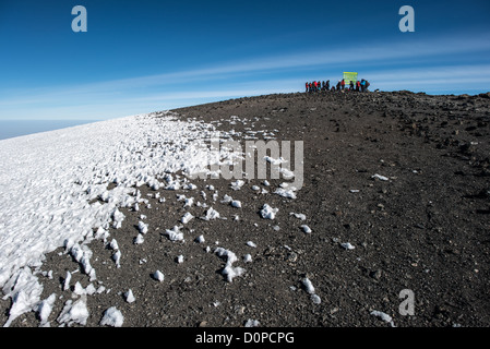 KILIMANDSCHARO, Tansania – Eine Gruppe von Kletterern posiert für Fotos neben dem Schild, das den Gipfel des Kilimandscharo (Uhuru Peak oder Kibo Summit) (19.341 m) markiert. Stockfoto