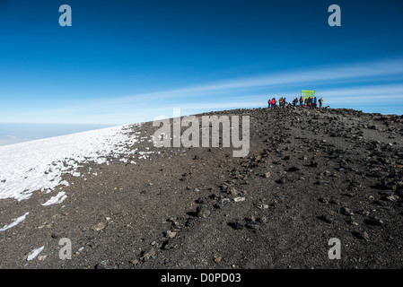 KILIMANDSCHARO, Tansania – Eine Gruppe von Kletterern posiert für Fotos neben dem Schild, das den Gipfel des Kilimandscharo (Uhuru Peak oder Kibo Summit) (19.341 m) markiert. Stockfoto