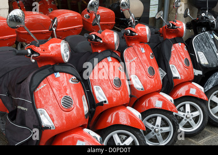 Paris, Frankreich: Rote Piaggio Vespa Motorroller zu mieten - in einer Reihe vor einem Verleih geparkt. Stockfoto