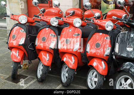 Paris, Frankreich: Rote Piaggio Vespa Motorroller zu mieten - in einer Reihe vor einem Verleih geparkt. Stockfoto