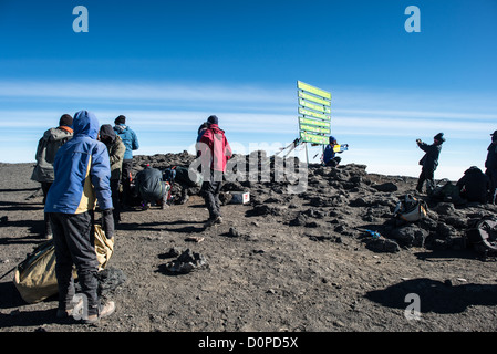 KILIMANDSCHARO, Tansania – Kletterer posieren für Fotos neben dem Schild, das den Gipfel des Kilimandscharo (19.341 m) markiert. Stockfoto