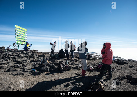 KILIMANDSCHARO, Tansania – Kletterer posieren für Fotos neben dem Schild, das den Gipfel des Kilimandscharo (19.341 m) markiert. Stockfoto