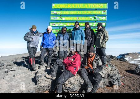 KILIMANDSCHARO, Tansania – Eine Gruppe von Kletterern posiert für ein Foto neben dem Schild, das den Uhuru Peak markiert, den höchsten Gipfel des Kilimandscharo (und höchsten Punkt in Afrika). Stockfoto