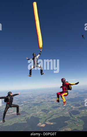 Fallschirmspringer ist eine bunte Luftschlauch in seiner Hand hält und ein weiterer Taucher sind in einer Position sitzen um ihn herum fliegen. Stockfoto