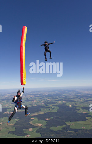 Fallschirmspringer ist eine bunte Luftschlauch in seiner Hand hält und ein weiterer Taucher nähert sich ihm von oben in einer Position sitzen. Stockfoto