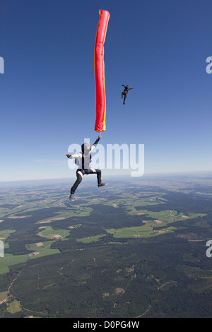 Fallschirmspringer ist eine bunte Luftschlauch in seiner Hand hält und ein weiterer Taucher nähert sich ihm von oben in einem Stand-up Position. Stockfoto