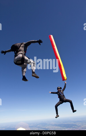 Fallschirmspringer ist eine bunte Luftschlauch in seiner Hand hält und ein weiterer Taucher nähert sich ihm von oben in einer Position sitzen. Stockfoto