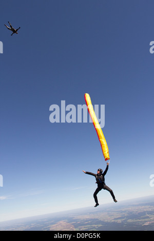 Fallschirmspringer ist eine bunte Luftschlauch in seiner Hand hält und eine andere Taucher nähert sich ihm von oben in einer Tracking-Position. Stockfoto