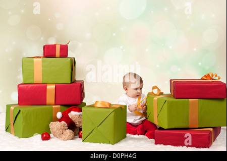 Baby sitzt zwischen Weihnachten präsentiert auf Bokeh Hintergrund Stockfoto