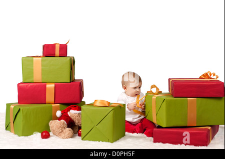 Baby sitzt zwischen Weihnachten präsentiert, isolierten auf weißen Hintergrund Stockfoto