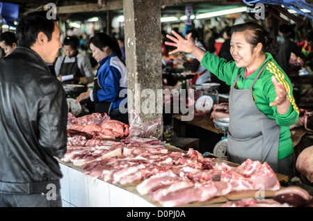 Ein Metzger spricht mit einem Kunden bei großen und belebten Morgenmarkt in Phonsavan im nordöstlichen Laos. Der Markt hat keine Kühlung so Anbieter genau, wieviel verderblichen Lebensmittel vorherzusagen müssen, an einem bestimmten Tag zu löschen. Die Menschen in der Region sind überwiegend Hmong Ethnizität. Stockfoto