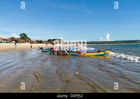 Muslimische Fischer schob ihr Boot auf das Meer am Strand von Jimbaran auf Bali, Indonesien Stockfoto