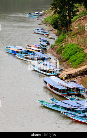 NONG KHIAW, Laos - zahlreiche Boote sind entlang der Stadt Waterfront in Nong Khiaw in Nordlaos vertäut. Diese Aufnahme, von der Hohen Brücke überspannt den Fluß genommen, bietet einen erhöhten Blick auf den Hafen. Stockfoto