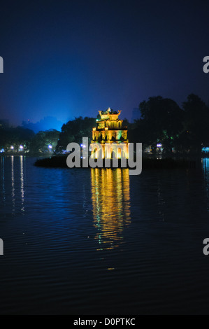 HANOI, Vietnam – der Schildkrötenturm (Thap Rua), beleuchtet bei Nacht, steht auf einer kleinen Insel im Hoan Kiem See im Zentrum von Hanoi. Das historische Denkmal, das 1886 während der französischen Kolonialzeit erbaut wurde, erinnert an die legendäre Geschichte der goldenen Schildkröte des Sees. Die Lichter der umliegenden Gebäude spiegeln sich unter einem tiefblauen Abendhimmel auf der Oberfläche des Sees. Stockfoto