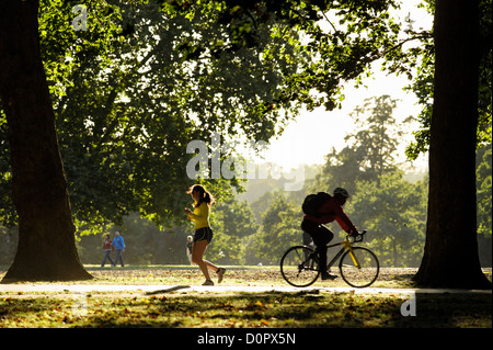 Ein junges Mädchen joggt vorbei an einem Mann Radfahren in die entgegengesetzte Richtung, Hyde Park Stockfoto