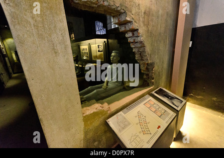 HANOI, Vietnam — ein Teil der ursprünglichen Mauer wurde abgeschnitten und durch Glas ersetzt, so dass Besucher in die kleinen, dunklen Zellen entlang der Todesrwo im Hoa Lo Gefängnis in Hanoi sehen können. Eine Plastikpuppe illustriert die Bedingungen. Im Westen besser bekannt als „The Hanoi Hilton“, ist ein Teil des Gefängnisses als Museum erhalten. Stockfoto