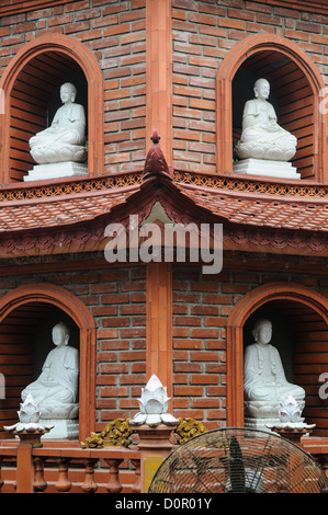 Tran Quoc Pagode Buddha Statuen Hanoi Vietnam // HANOI, Vietnam — Weiße Buddha Statuen befinden sich in kleinen Nischen im Backsteinturm der Tran Quoc Pagode am Westsee. Der mehrstöckige Turm mit traditionellen vietnamesischen buddhistischen architektonischen Elementen dient sowohl als religiöses Denkmal als auch als künstlerische Ausstellung. Dieses architektonische Merkmal befindet sich auf der Insel Kim Ngu und veranschaulicht die anspruchsvollen Designelemente der vietnamesischen Tempelarchitektur. Stockfoto