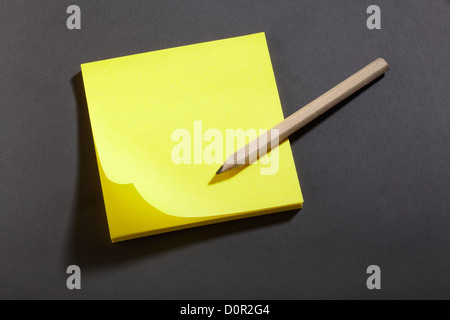 Gelber Aufkleber Hinweis und Bleistift auf Tafel Stockfoto