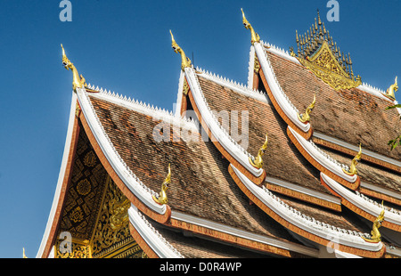 LUANG PRABANG, Laos – die kunstvolle Fassade und die steil abgewinkelte Dachlinie von Haw Pha Bang (Schlosskapelle) im Königlichen Palastmuseum in Luang Prabang, Laos. Dieses elegante Gebäude, das 1963 begonnen wurde, zeigt traditionelle laotische Architekturelemente mit seinen komplizierten Details und dem dramatischen Dach. Stockfoto