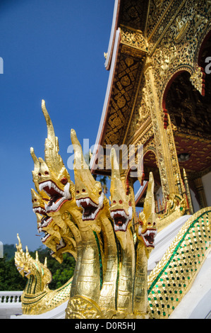 LUANG PRABANG, Laos – Goldene Naga (König Cobras) zieren die Treppe von Haw Pha Bang (Schlosskapelle) im Königlichen Palastmuseum in Luang Prabang, Laos. Die kunstvoll verzierte Kapelle in der nordöstlichen Ecke des Museumsgeländes zeigt traditionelle laotische Architektur und buddhistische Symbolik. Stockfoto