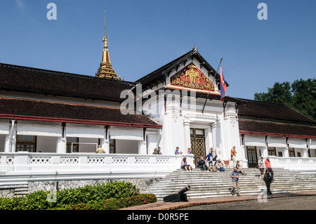 LUANG PRABANG, Laos – Touristen versammeln sich auf der Treppe des Hauptpalastgebäudes im Königlichen Palastmuseum in Luang Prabang, Laos. Diese ehemalige königliche Residenz, auch bekannt als Haw Kham, dient heute als Museum für laotische Geschichte und Kultur. Stockfoto