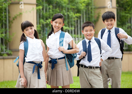 Porträt der niedlichen Schulkinder in Uniform am Schulhof Stockfoto