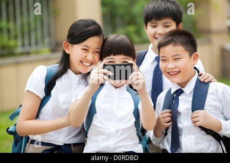 Aufgeregt Schulkinder in Uniform macht eine Selbstporträt Fotografie mit Smartphone Stockfoto