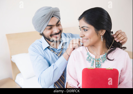 Mann, der eine Kette am Hals einer Frau Stockfoto