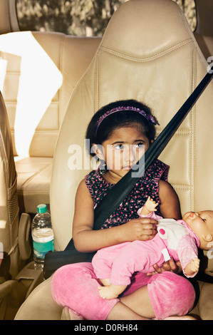 Mädchen in einem Auto sitzen und halten eine Puppe Stockfoto