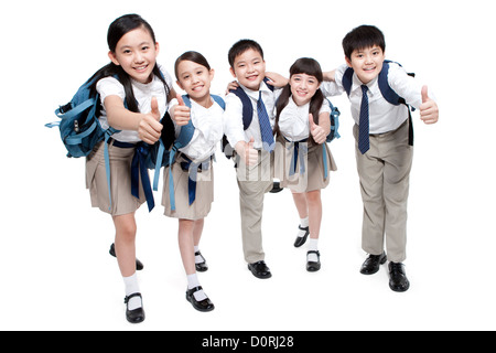 Fröhliche Schulkinder auftauchend Daumen mit Schulranzen auf dem Rücken Stockfoto