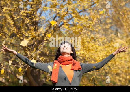 Glückliche junge Frau genießen goldenes Laub Stockfoto