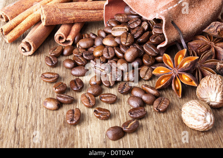 Kaffeebohnen mit Gewürzen sind auf hölzernen Hintergrund verteilt. Stockfoto