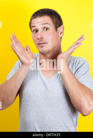 Überrascht, junger Mann mit Händen in der Luft, auf gelbem Hintergrund Stockfoto