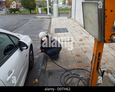 Junge Frau Auto Reifendruck prüfen Stockfoto