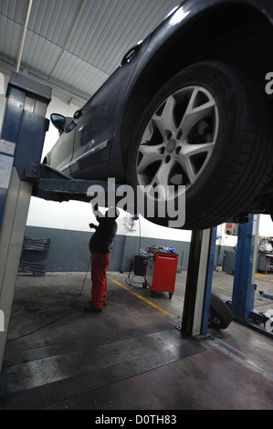 Kfz-Mechaniker überprüft ein Auto auf einer Hebebühne angehoben Stockfoto
