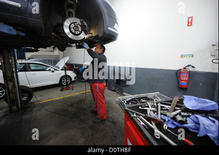 Kfz-Mechaniker überprüft ein Auto auf einer Hebebühne angehoben Stockfoto