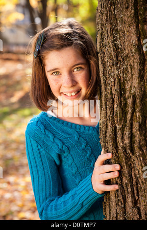 Junges Mädchen spähen rund um Baum, USA Stockfoto