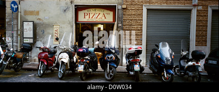 Eine Linie der Roller geparkt vor einer Pizzeria in Rom, Italien. Stockfoto
