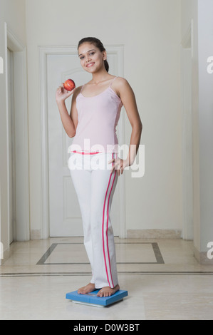 Frau hält einen Apfel und auf eine Waage stehen Stockfoto