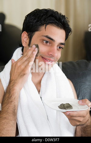 Nahaufnahme eines Mannes Moorpackung auf seinem Gesicht auftragen Stockfoto