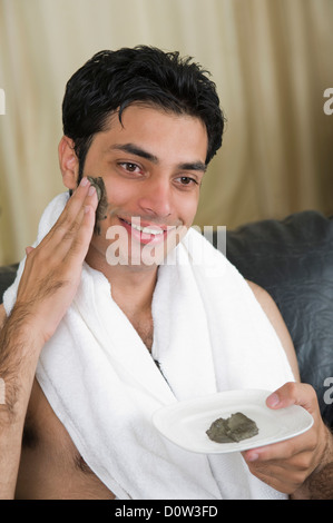 Nahaufnahme eines Mannes Moorpackung auf seinem Gesicht auftragen Stockfoto