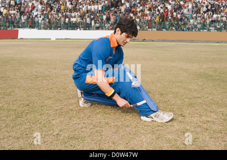 Cricketspieler anpassen seiner Schienbeinschutz Stockfoto