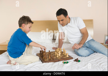 Mann und sein Sohn spielt Schach auf dem Bett Stockfoto