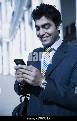 Nahaufnahme von einem Geschäftsmann SMS auf dem Handy und lächelnd, Gurgaon, Haryana, Indien Stockfoto