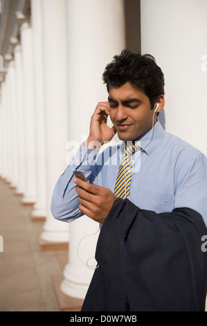 Geschäftsmann, anhören von MP3-Player, Gurgaon, Haryana, Indien Stockfoto