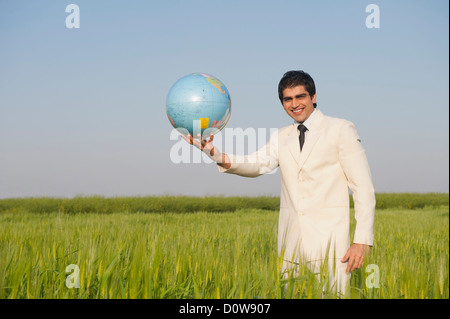 Geschäftsmann zeigt eine Kugel in einem Weizenfeld Stockfoto