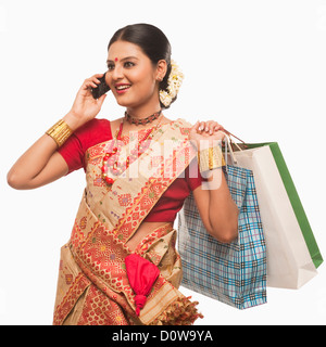 Frau telefonieren mit einem Handy und halten Einkaufstaschen Stockfoto