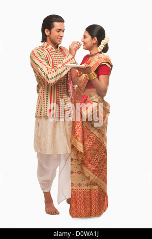 Mann, die Verfütterung von Prasad an eine Frau auf Bihu festival Stockfoto