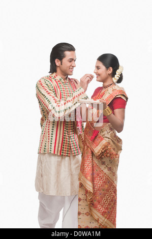 Mann, die Verfütterung von Prasad an eine Frau auf Bihu festival Stockfoto