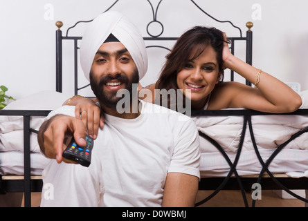 Sikh paar vor dem Fernseher im Schlafzimmer Stockfoto